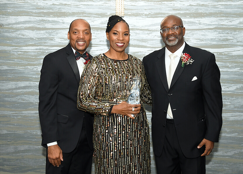 Two people standing around McGaw Y President who received an award.
