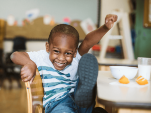 A young child smiling, kicking his leg up in the air