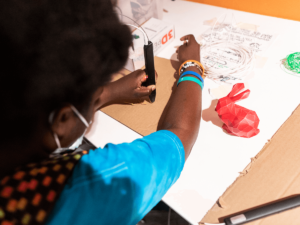 A young person cutting out a piece of wood.