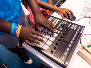 Two hands on a sound board creating music.