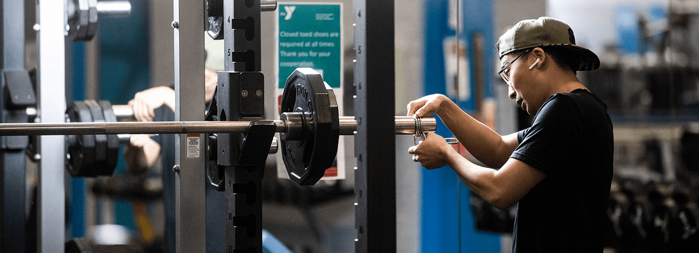 A person adjusting a weight lifting machine.