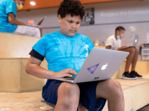 middle-school youth sitting with a laptop computer