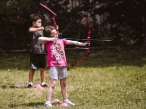 two children practicing archery outside