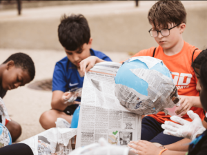 a group of children making paper mache art