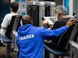 A personal trainer working with a client on equipment.