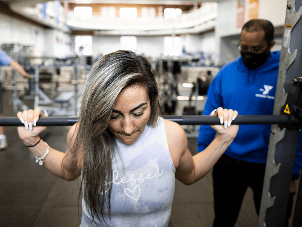 A personal trainer working with a client on weights.