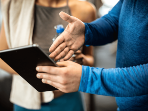 A close up of a personal trainer's hands pointing to a tablet