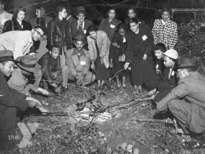 A group of Black people around the campfire in 1950s