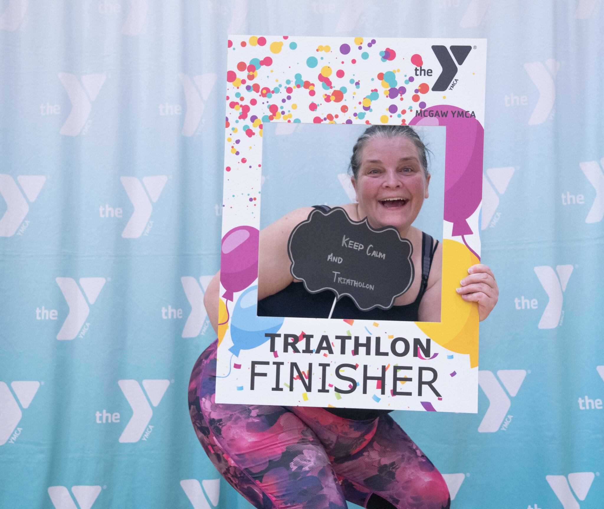 A person smiling holding a photo frame after finishing the McGaw Y triathlon