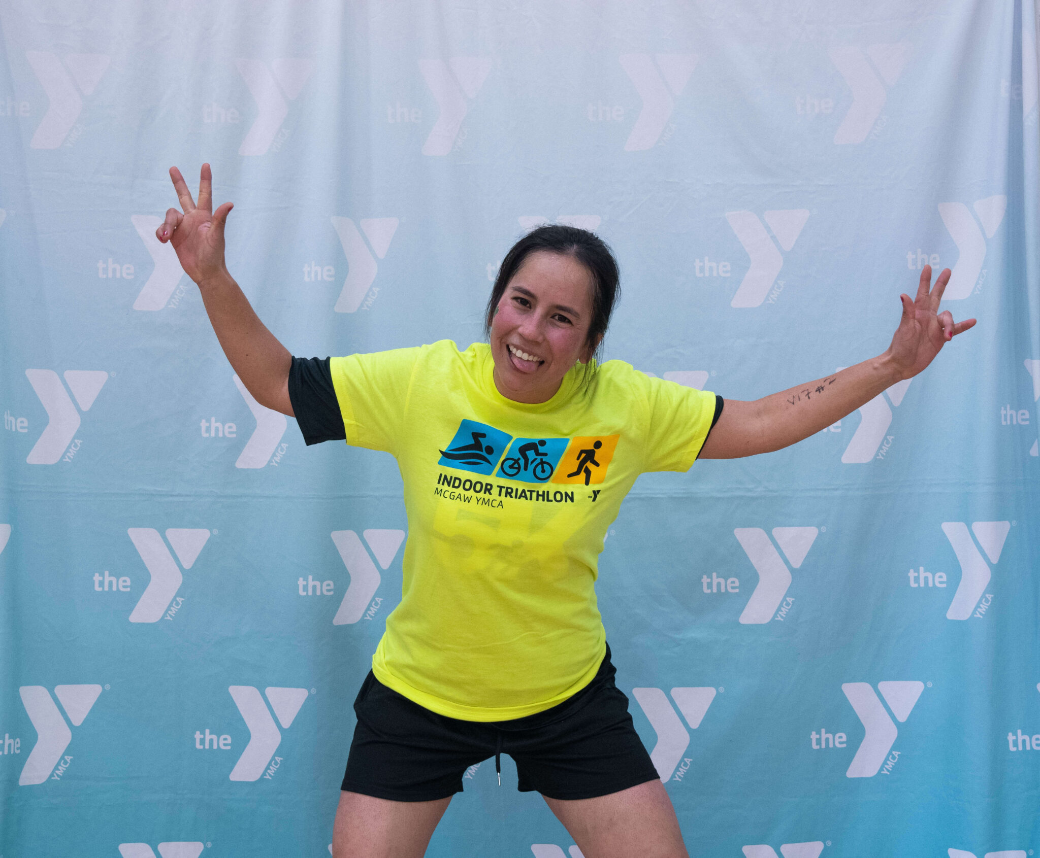 A person smiling with peace signs up after finishing the McGaw Y triathlon