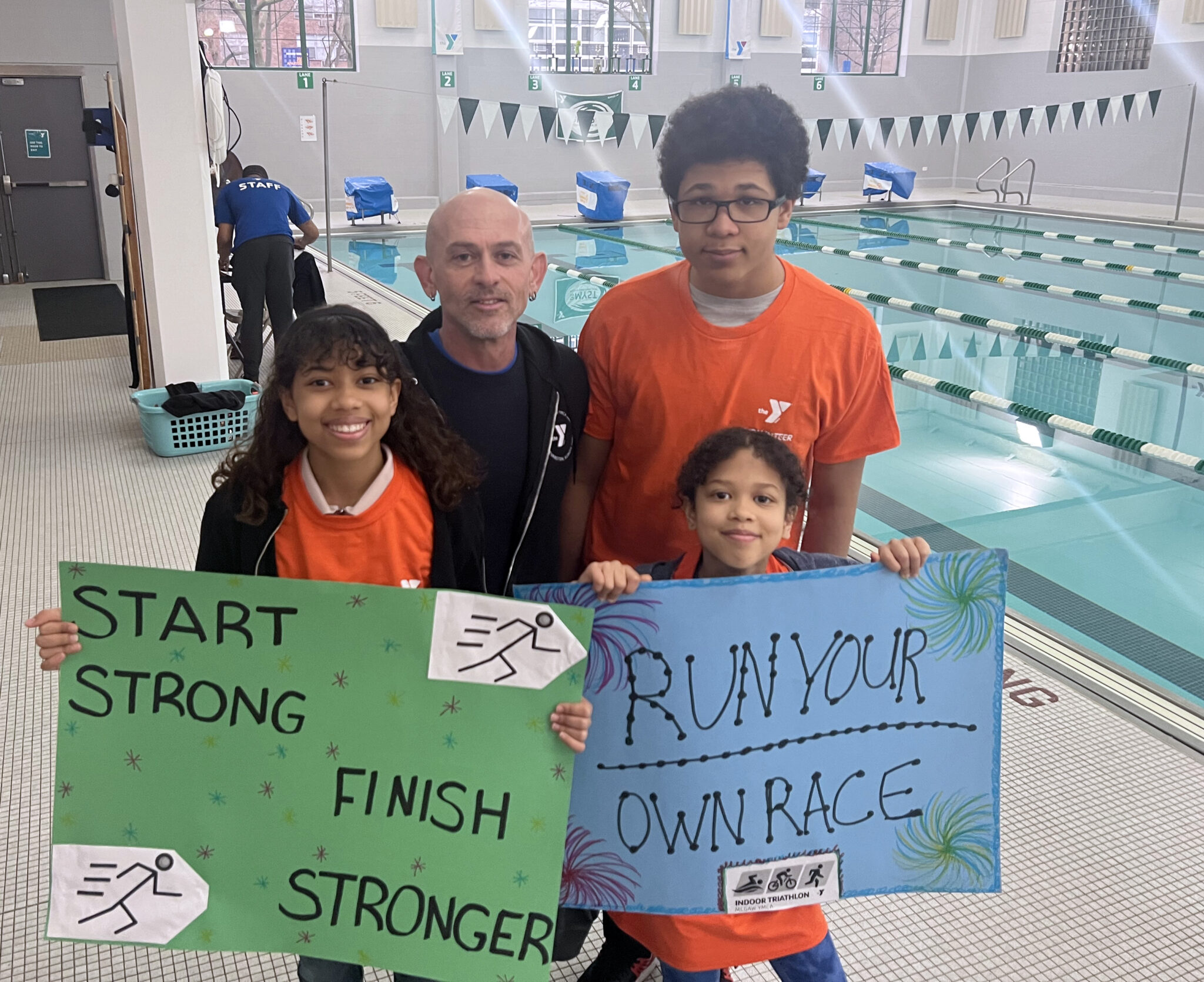 Volunteers smiling and holding signs at the triathlon.