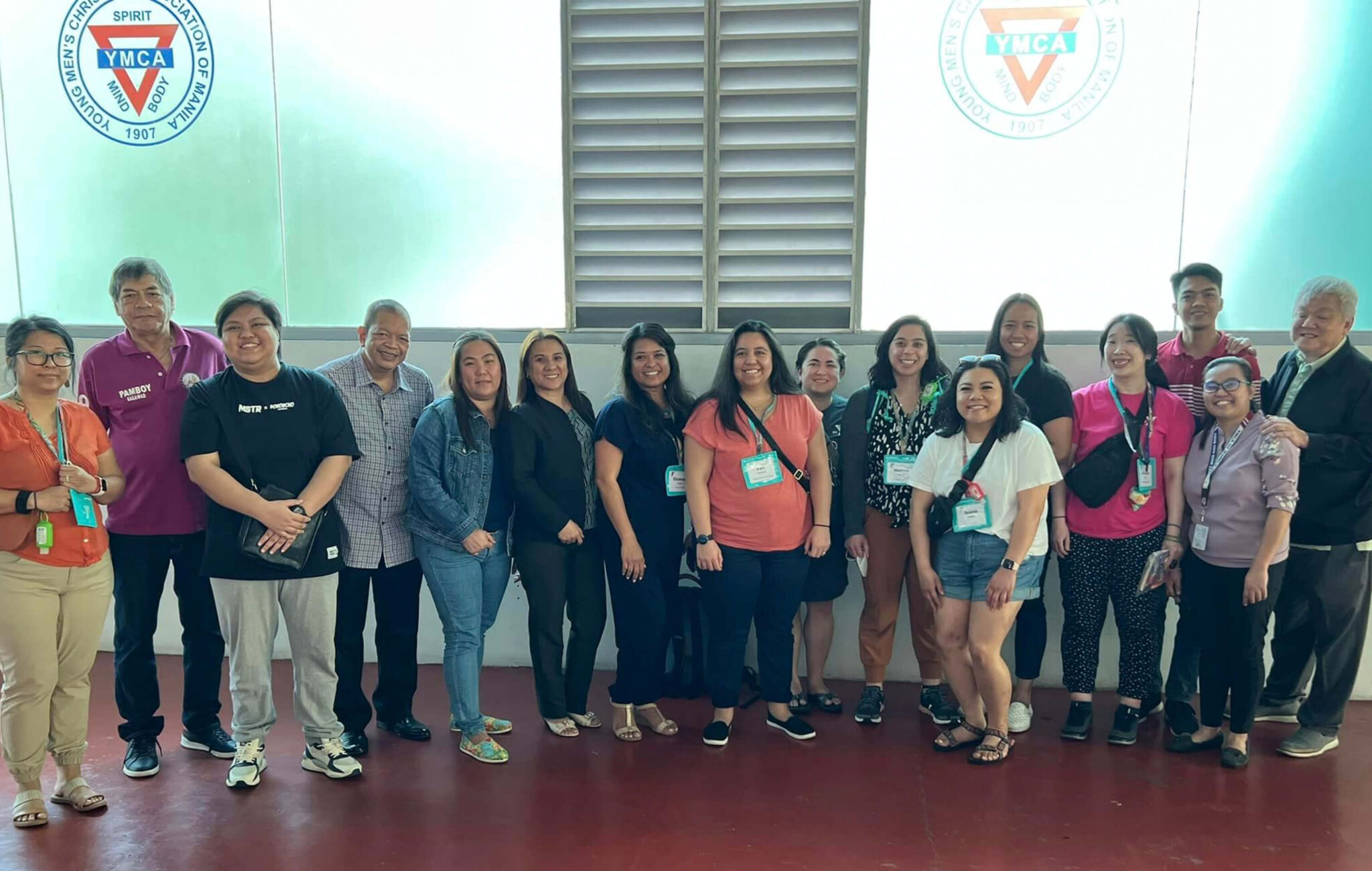 A group of people stand in front of a glass wall with a YMCA logo on it.
