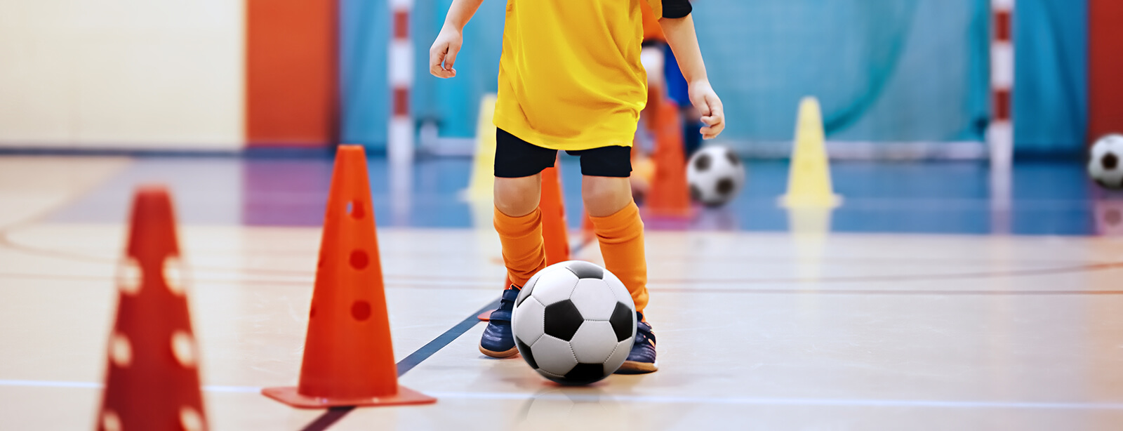An closeup image of a child's feet playing indoor soccer.