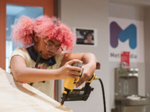 A middle school youth drilling wood at YMCA Meta Meets Camp.