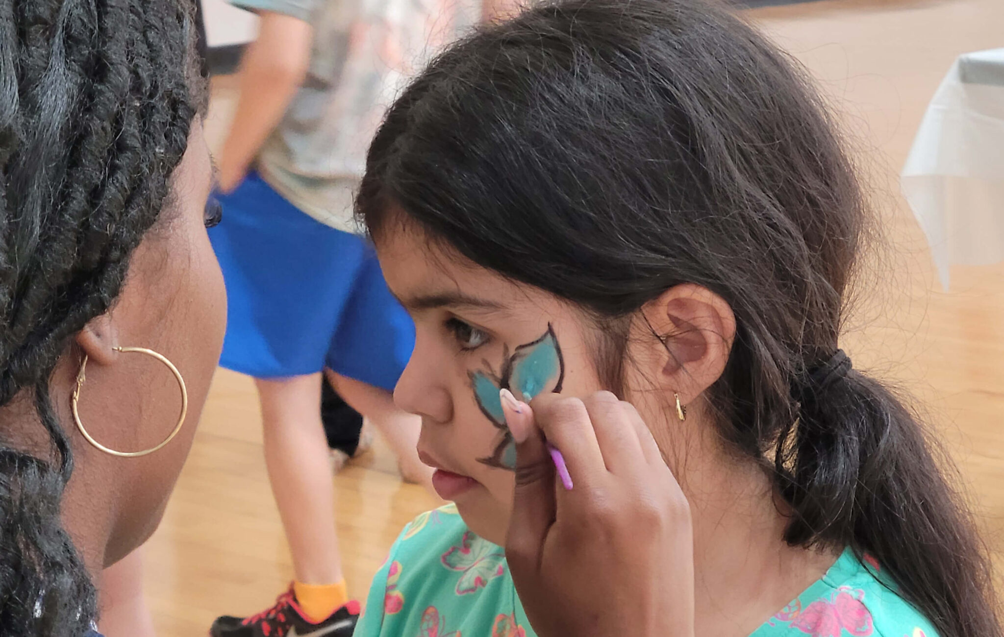 A child getting a face painting of a butterfly.