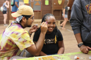 An adult painting a child's face at Family Camp Carnival.