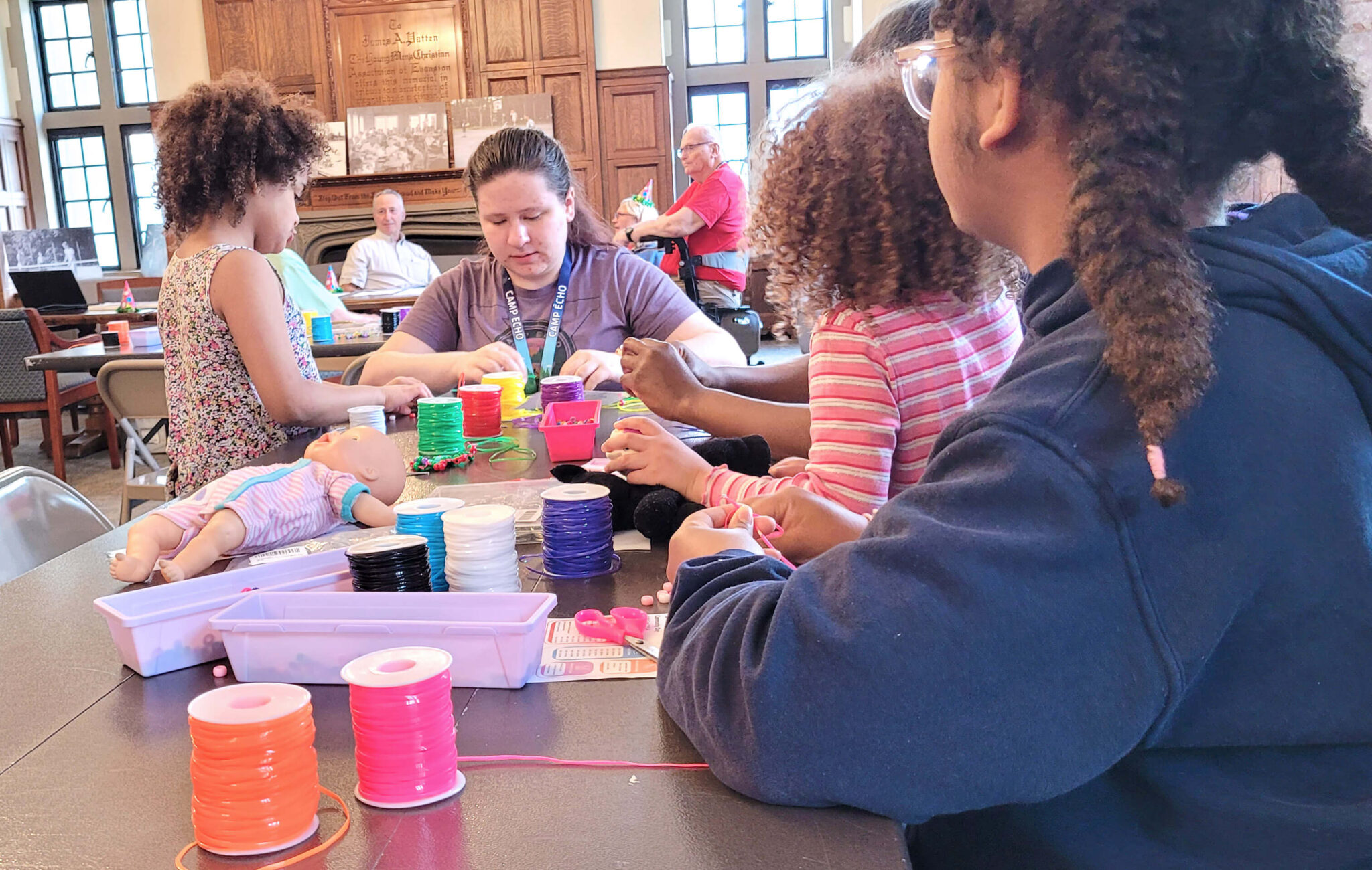 A group of children at a craft table surrounded by neon string.