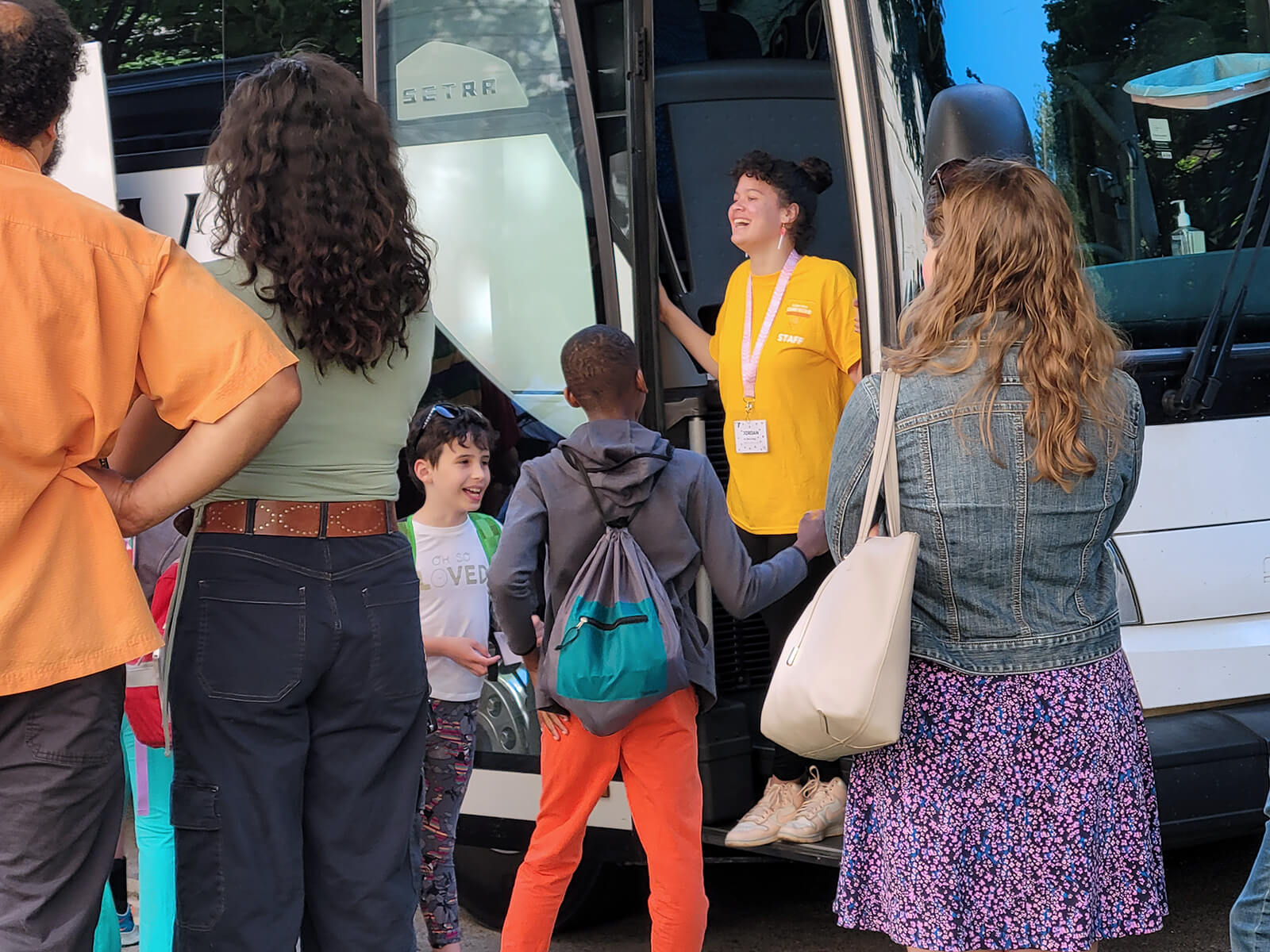 A Camp Echo staff member greeting campers at the bus door.