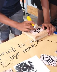 A young person is carving linoleum for block printing