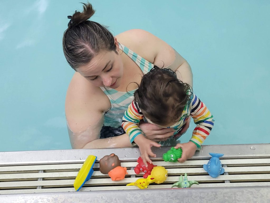 A parent with child in a pool.