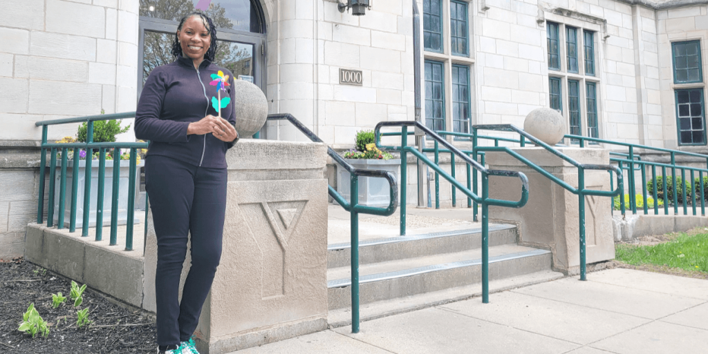 President/CEO Monique Parsons is pictured in front of the McGaw YMCA Main Building holding a pinwheel.