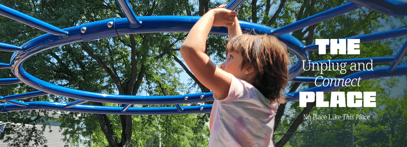 A kid playing on playground equipment outdoors.