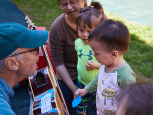 Mr Dave shows a guitar to kids.