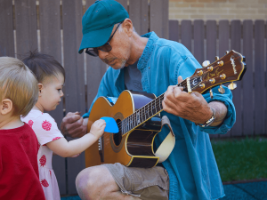 Mr. Dave shows a guitar to kids.