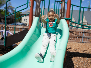 A young child slides down the playground equipment.
