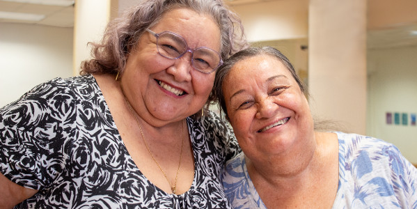 Edith and Sonia stand side by side in a group fitness studio, smiling.