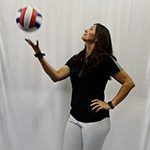 A photo of volleyball coach, Whitney Carson, tossing a volleyball in the air.