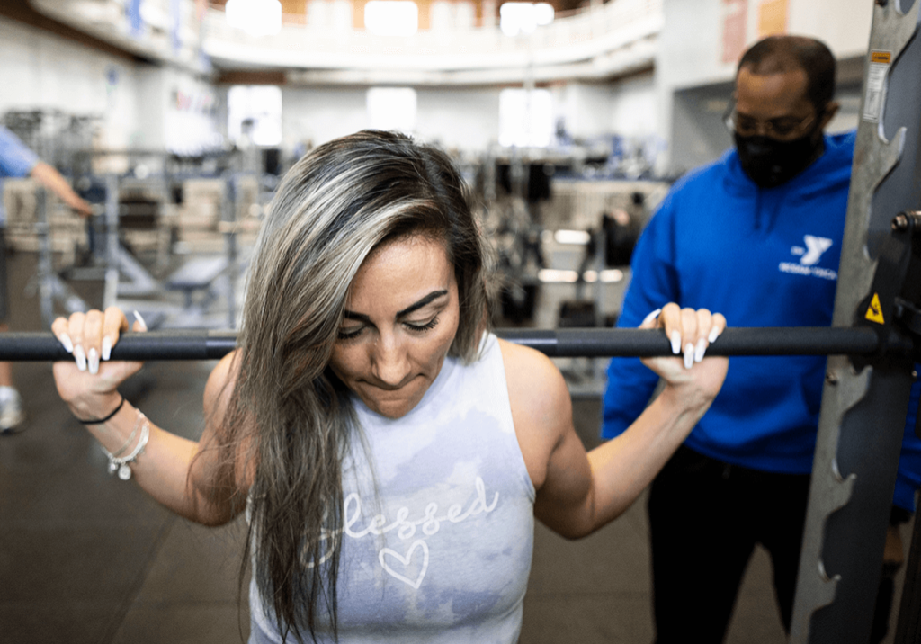 A personal trainer working with a client on weights.